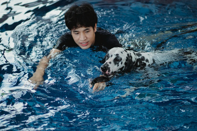 a young man swimming with his dog in the pool