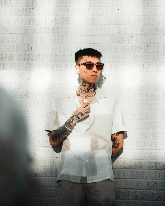 a man with tattoos and shades on holding a cigarette