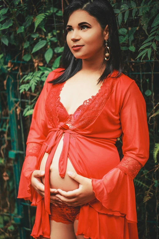 a pregnant girl in an orange dress poses for a po