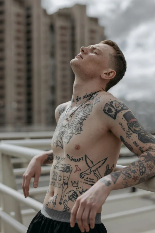 a man is standing on the ledge in a building with tattoos on his body