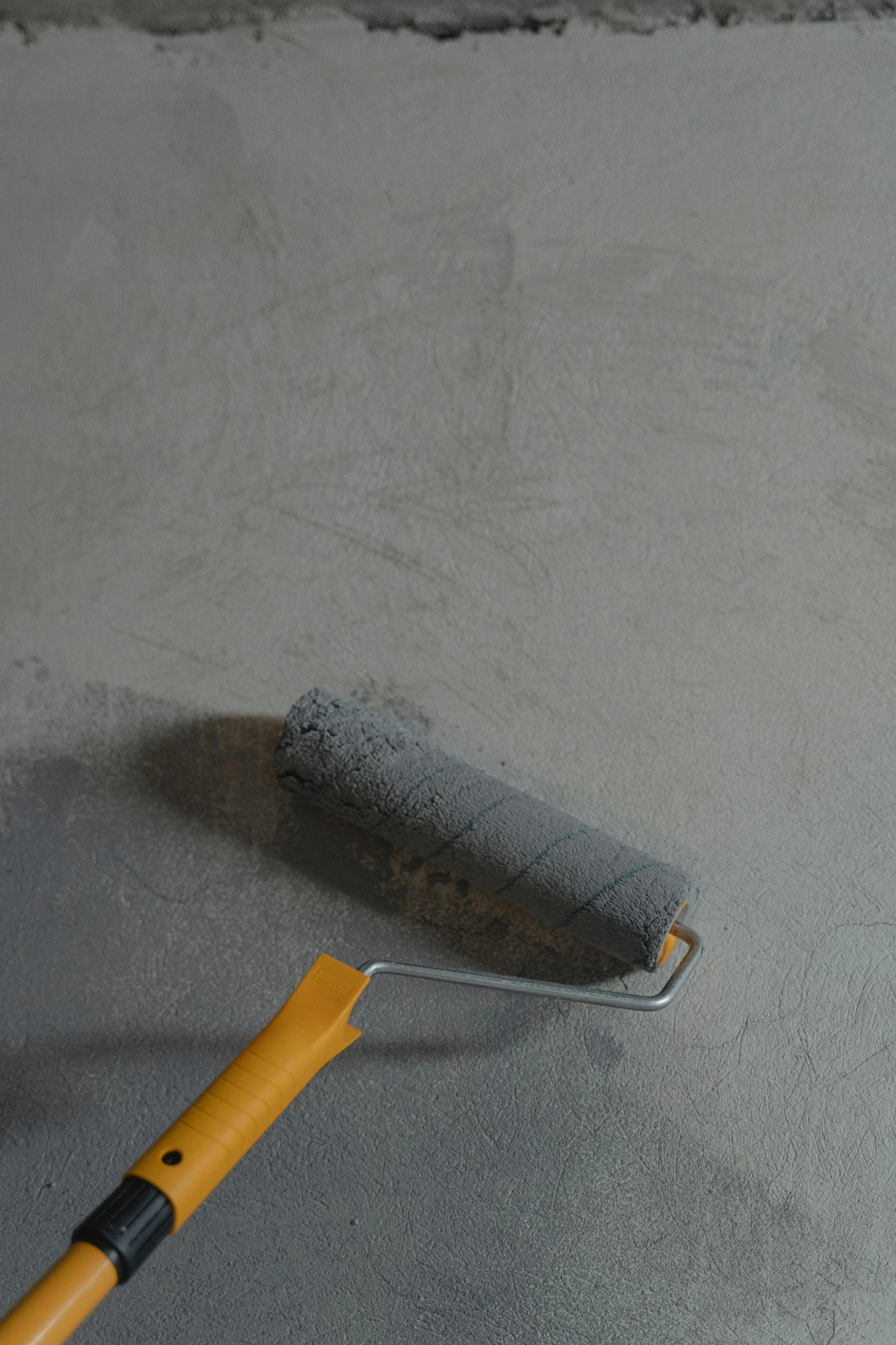 a yellow brush on the ground with grey cleaning on it