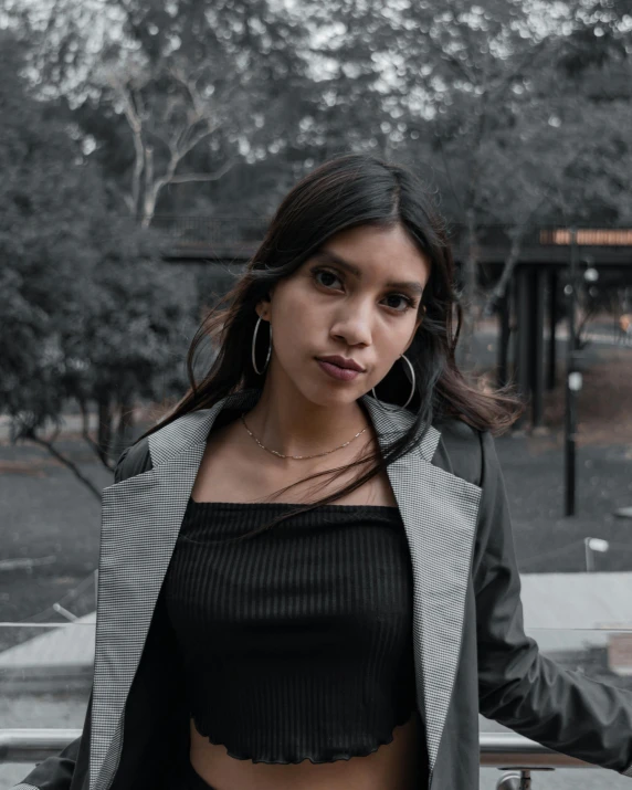 a  is standing outside on a park bench wearing a black crop top and jacket