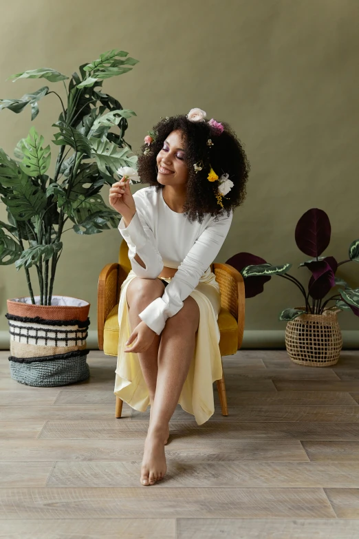 a  sitting on a chair next to a plant