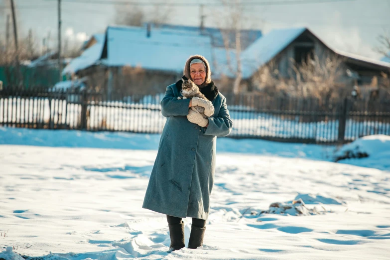 a woman is standing in the snow holding two dogs