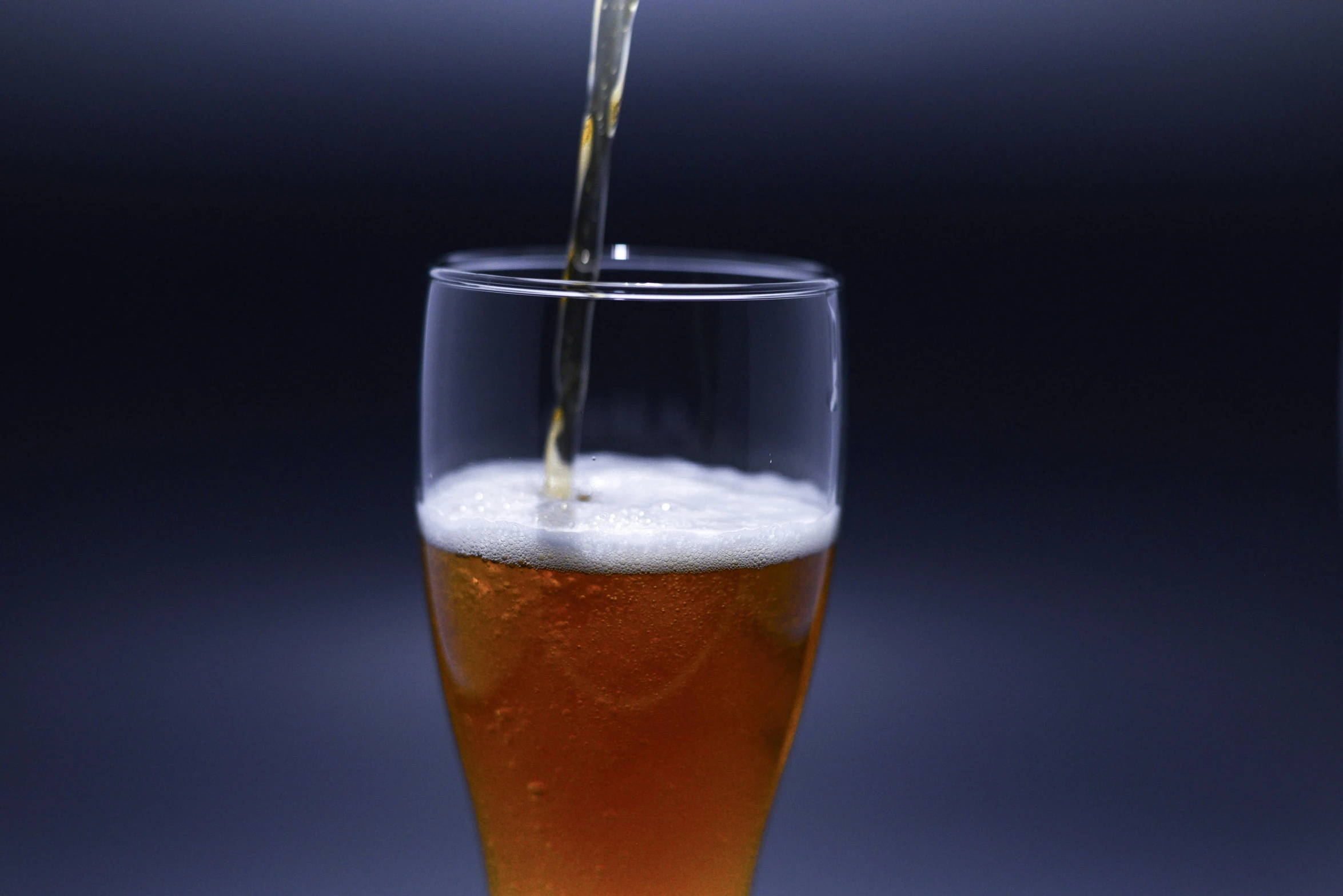 a glass filled with liquid and being poured into it