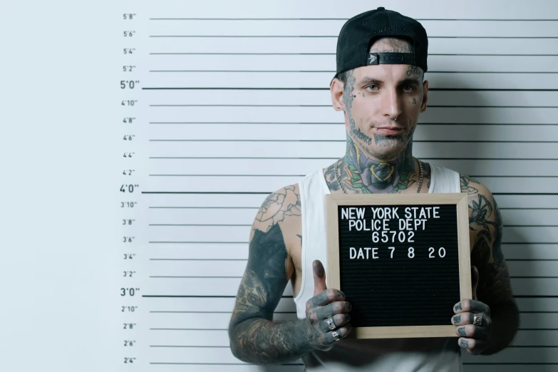 tattooed man in front of mugs holding black sign