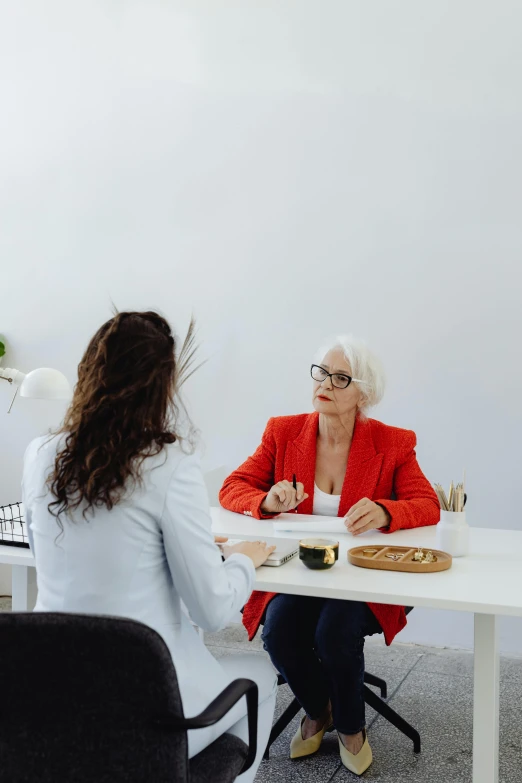 a woman sits at a table talking to another woman