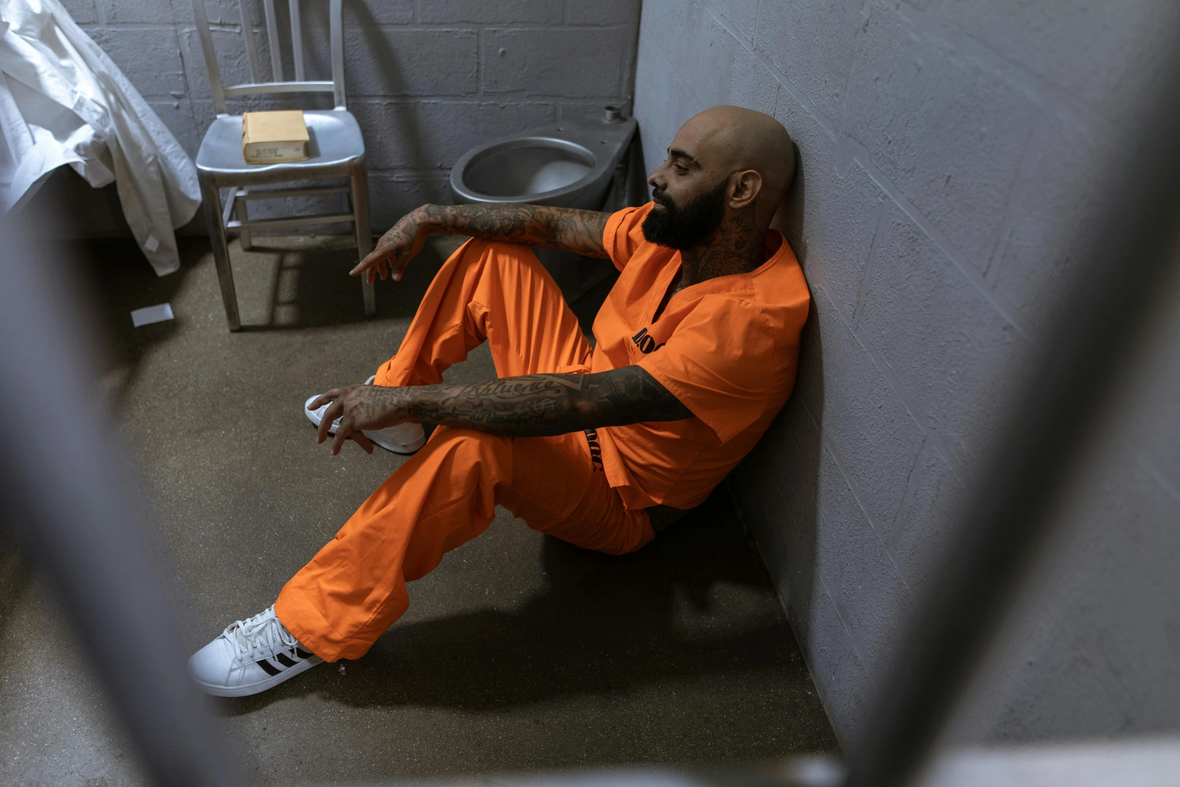 a man sits on the floor of a  cell