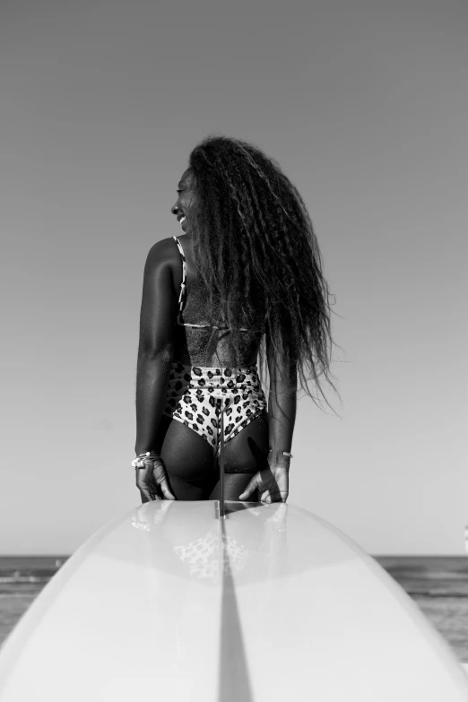 black and white pograph of woman standing on surfboard