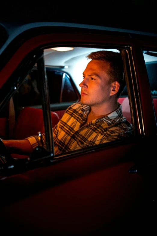 man driving a car at night near the light