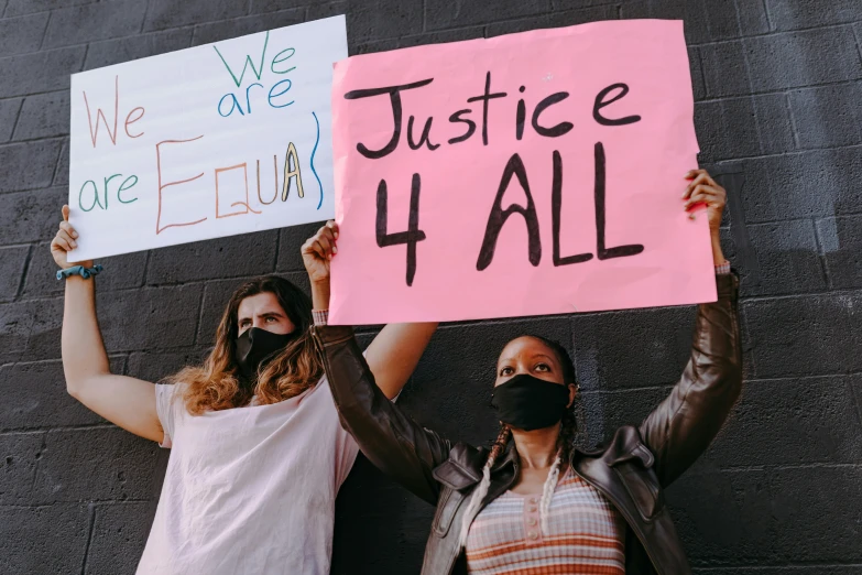 two women holding signs outside of a building