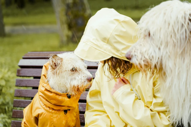 two little girls with blond hair, wearing raincoats and holding their dog
