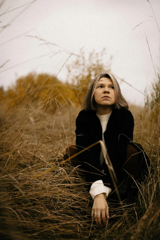 a beautiful blonde sitting on the grass with her arms folded