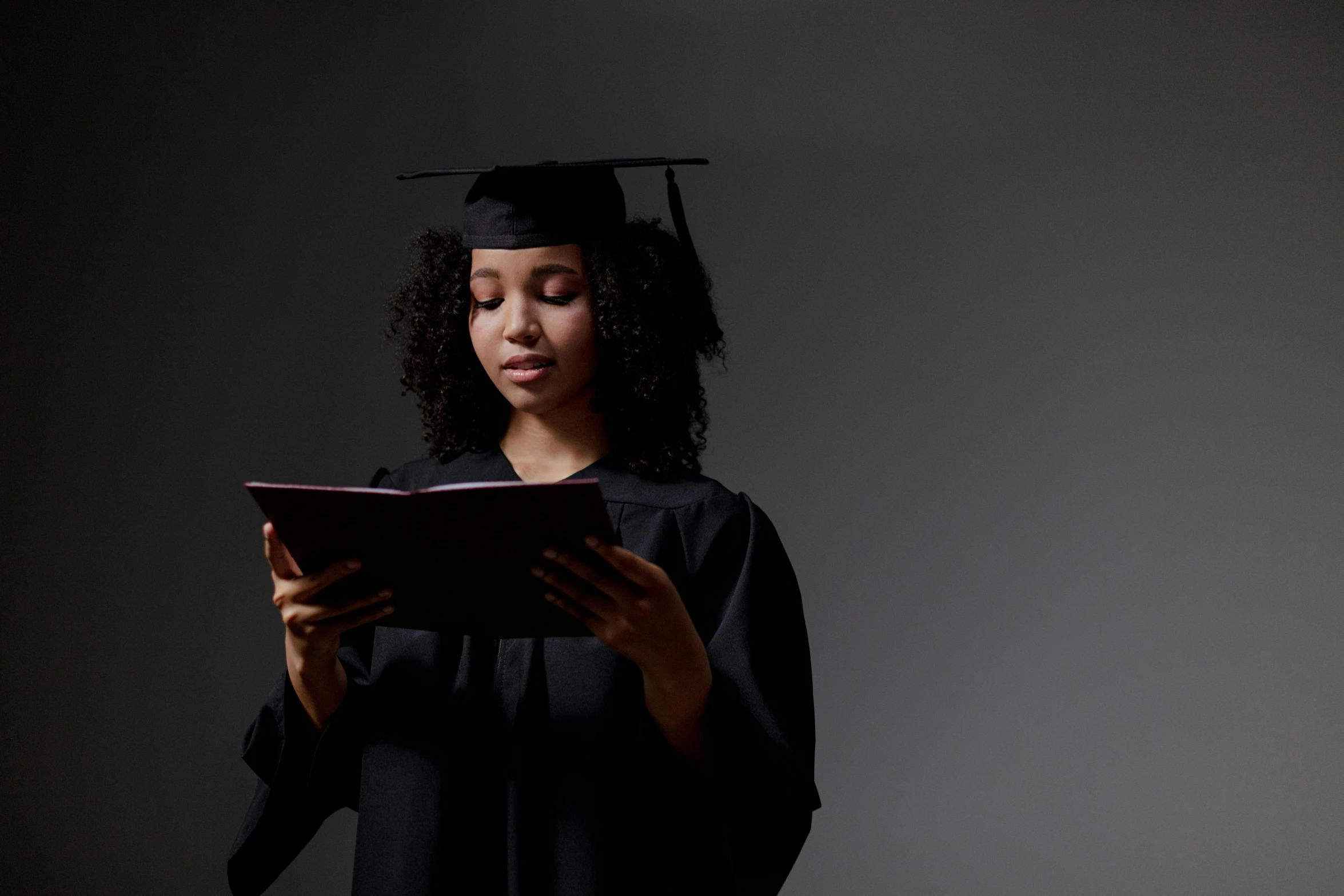 an african american woman reading a book in front of dark background