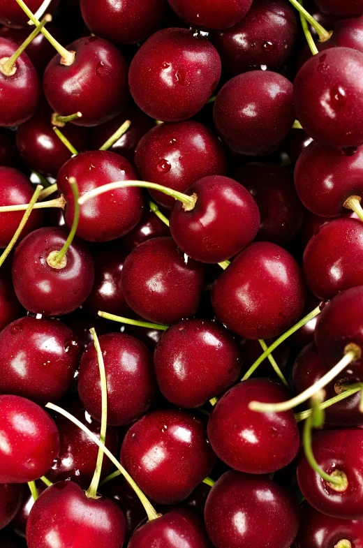 an arrangement of dark colored cherries are stacked up