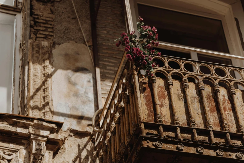 an old and rusty building with a flower on the balcony