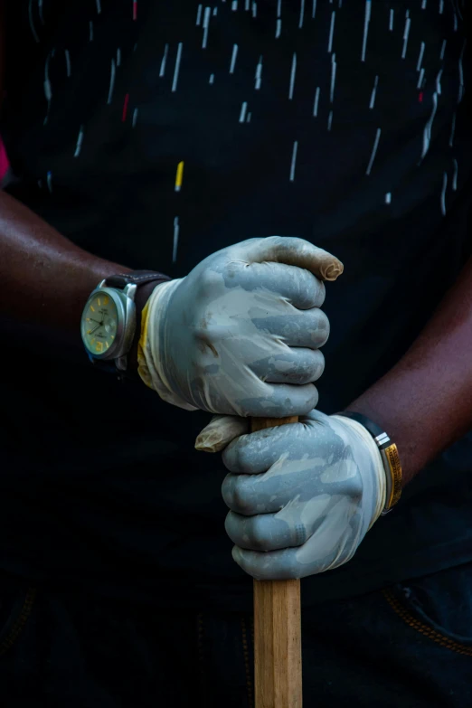 someone wearing gloves and holding on to a stick with a cigarette