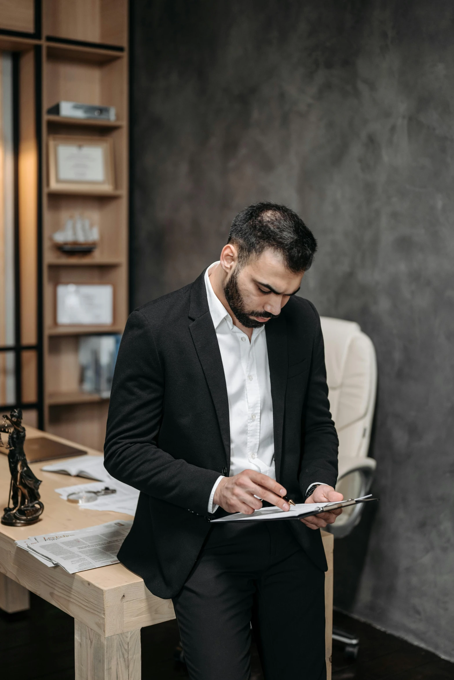 a man in a black suit looking at his tablet