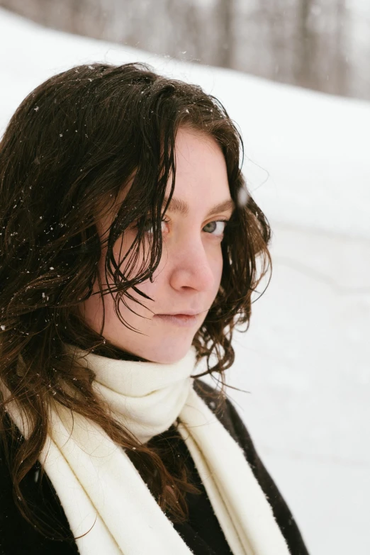 a girl with long brown hair stands in the snow