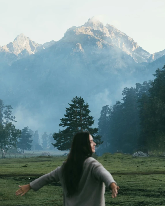 woman in a field with mountains and trees in the background