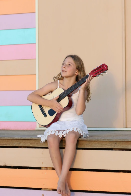 a girl with a guitar sits on the ledge