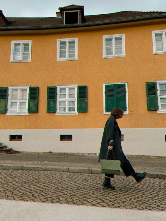 man walking past a tall building with many windows