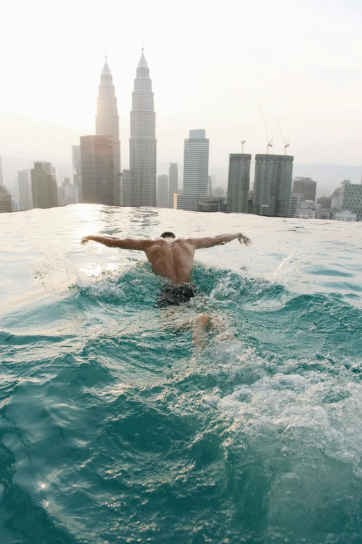 man swimming with large city skyline in the background