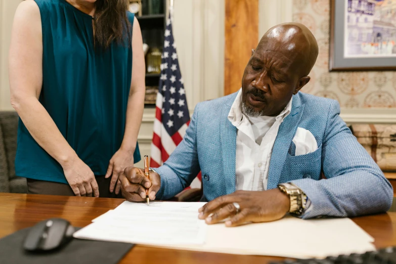 a woman looking on the man signing paperwork