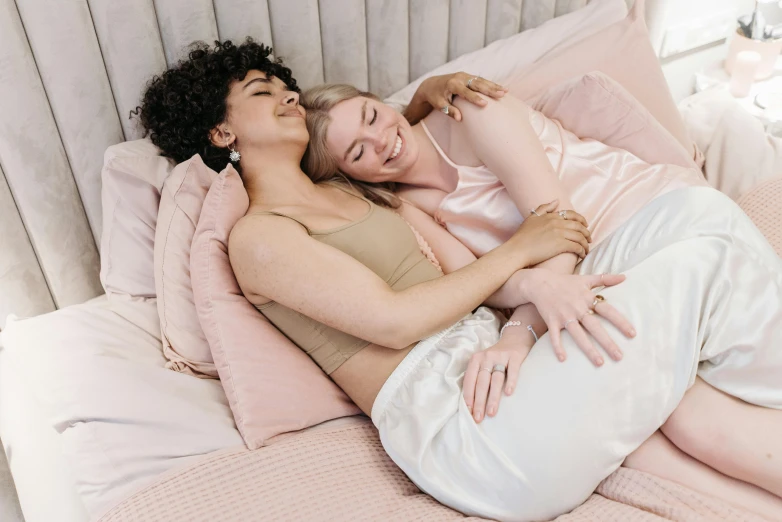 two women cuddled together in bed hugging each other