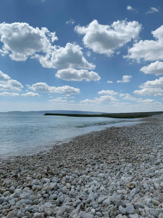 the sky and water are partly over rocks and pebbles