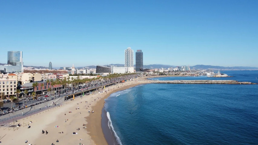 a group of people walking on a beach with a lot of tall buildings