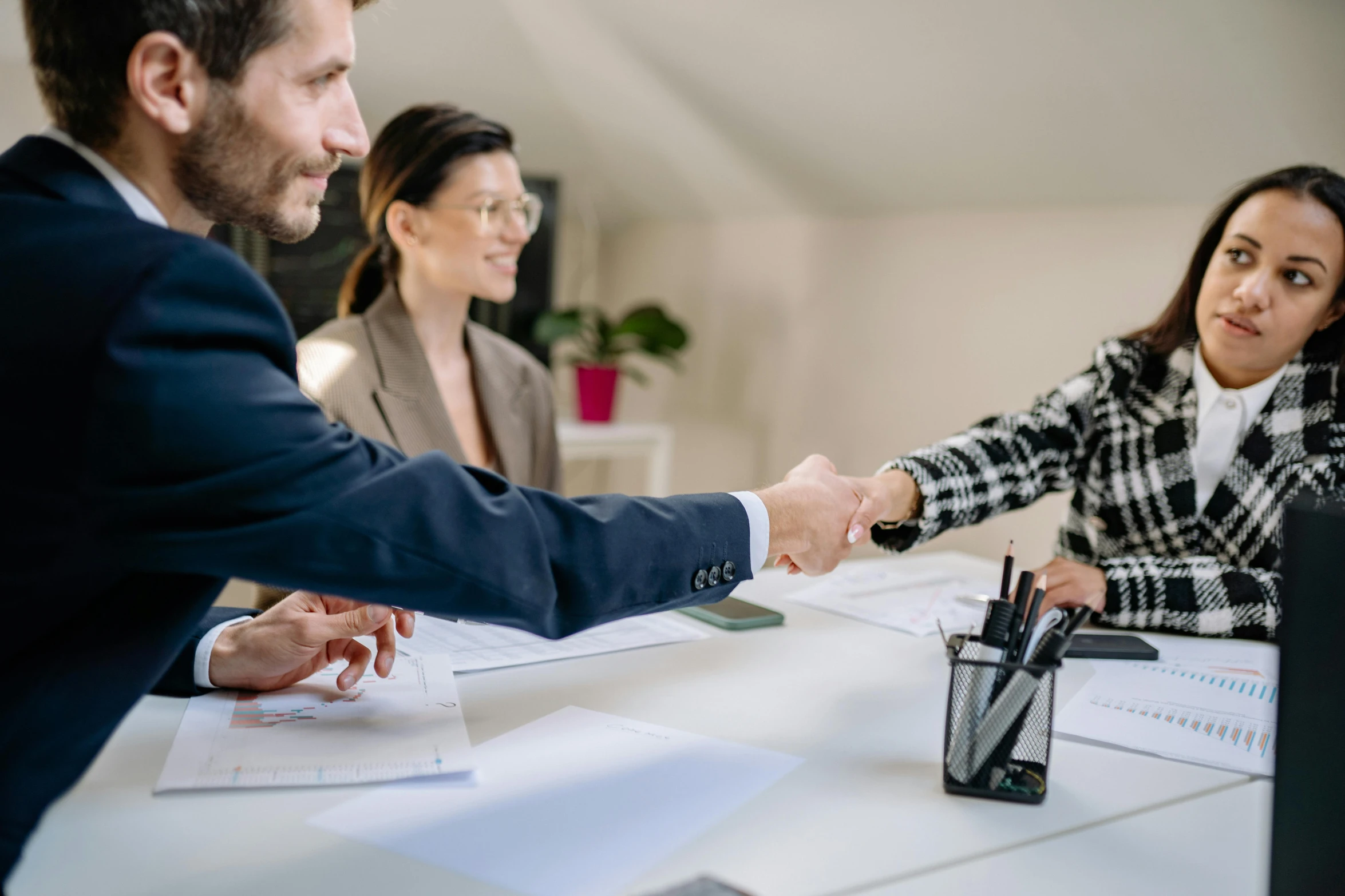 a woman is shaking hands with two men