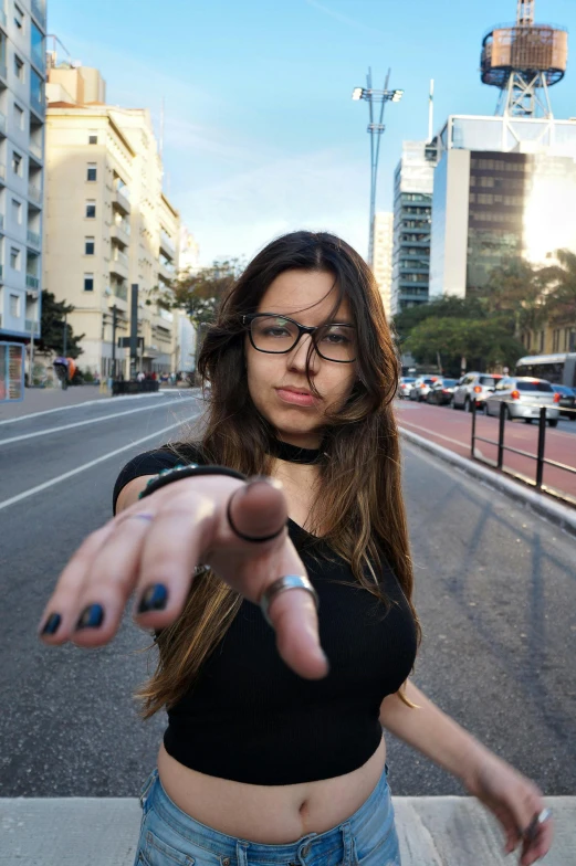 girl holding up finger with camera flash near road