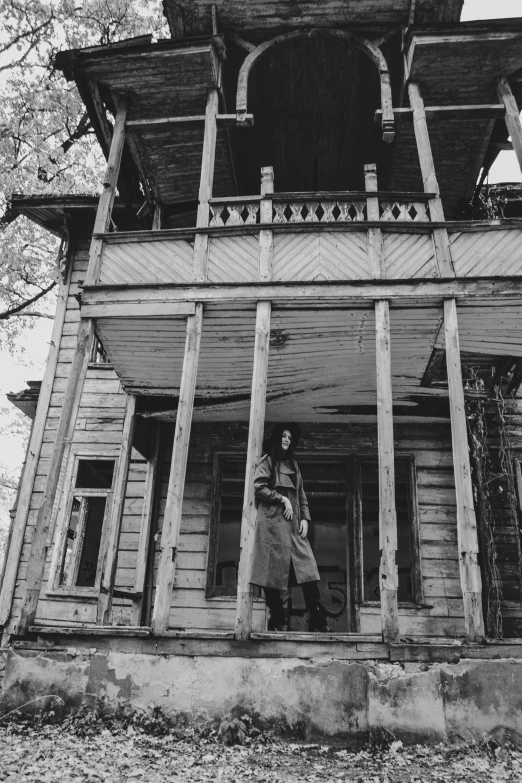 two people stand on the porch of an old, rundown house