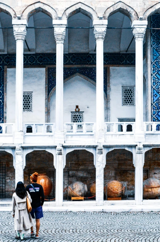 two women are looking at pottery items in a courtyard