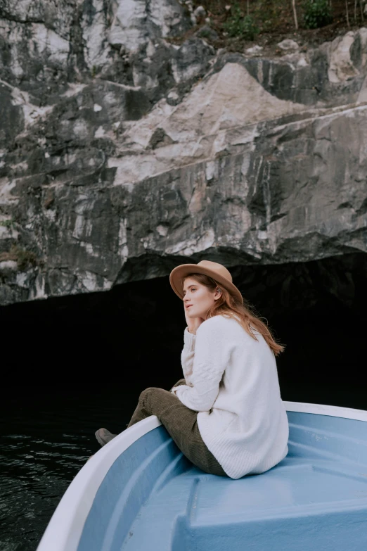 a woman wearing a brown hat sitting in the bow of a boat