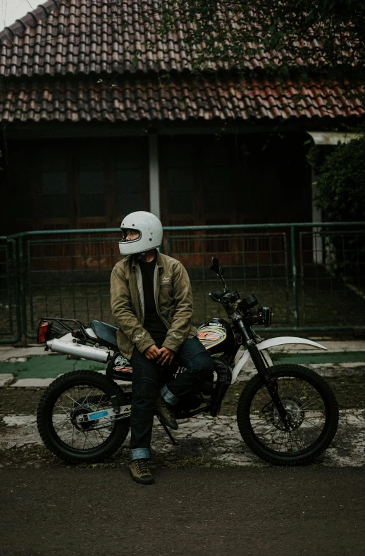 person in white helmet with black motorcycle sitting on pavement