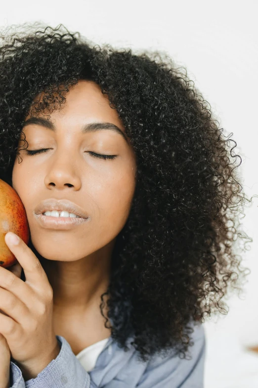 a woman is holding a piece of fruit up to her face