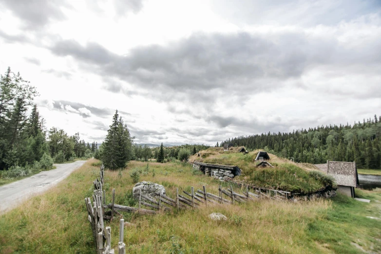 a dirt road passes an old wooden fence and barn