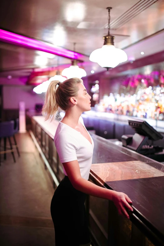 a woman is standing at a bar waiting for a band to perform