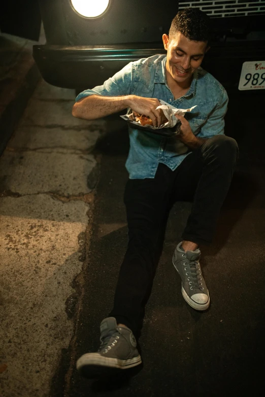 a man eating from a bag next to a street lamp