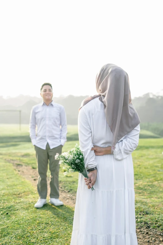 an older couple stands on a grass field