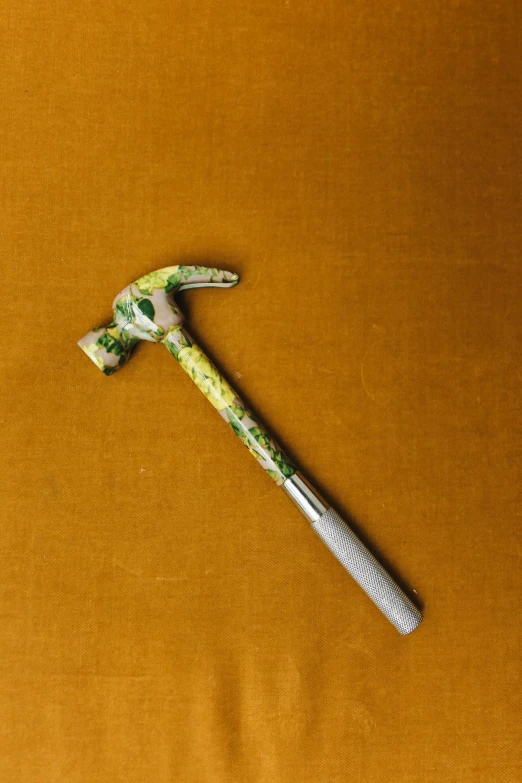 a decorated green floral hammer is lying on a brown surface