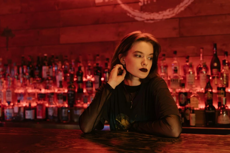 a woman talking on a cell phone in front of a bar filled with liquor bottles