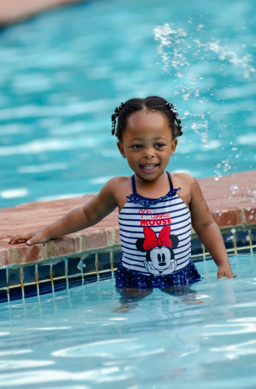 an adorable little girl in a pool next to a swimming board