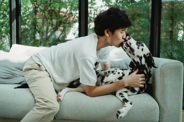 a man holding a dalmatian dog and licking its nose