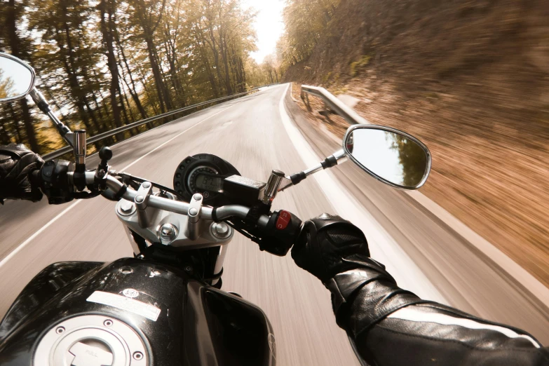 the view from a motorcycle mirror on a road