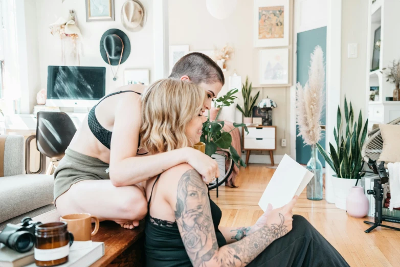 a tattooed woman hugging a tattooed man sitting on top of a couch