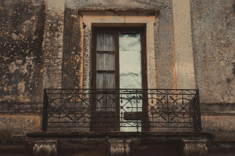 a window on an old building with a metal fence in front