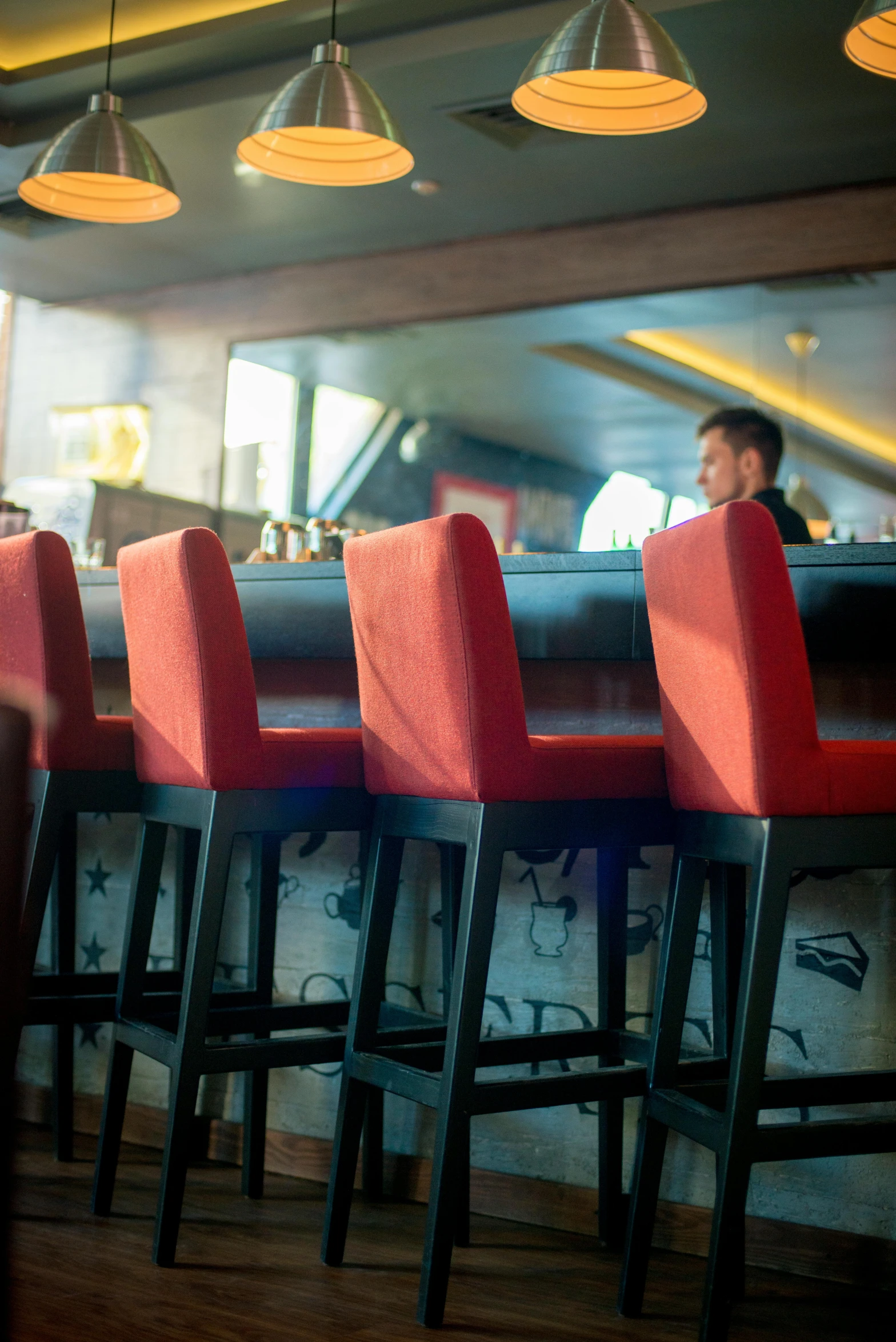 a man in a restaurant setting behind red bar stools